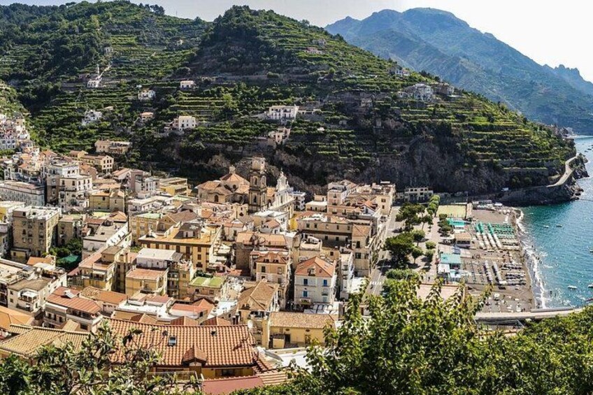 A coastal town with terraced vineyards, buildings, and a beach. 2