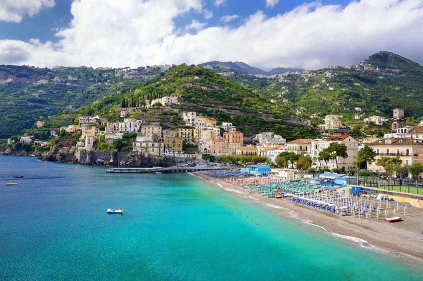 A coastal town with a beach, boats, and buildings on a hillside. 5