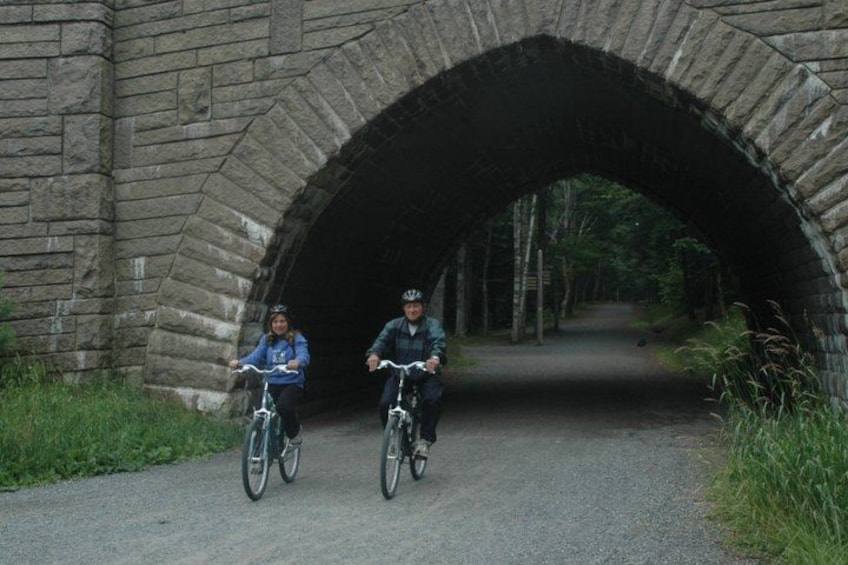 Two cyclists riding under a stone arch bridge. 4