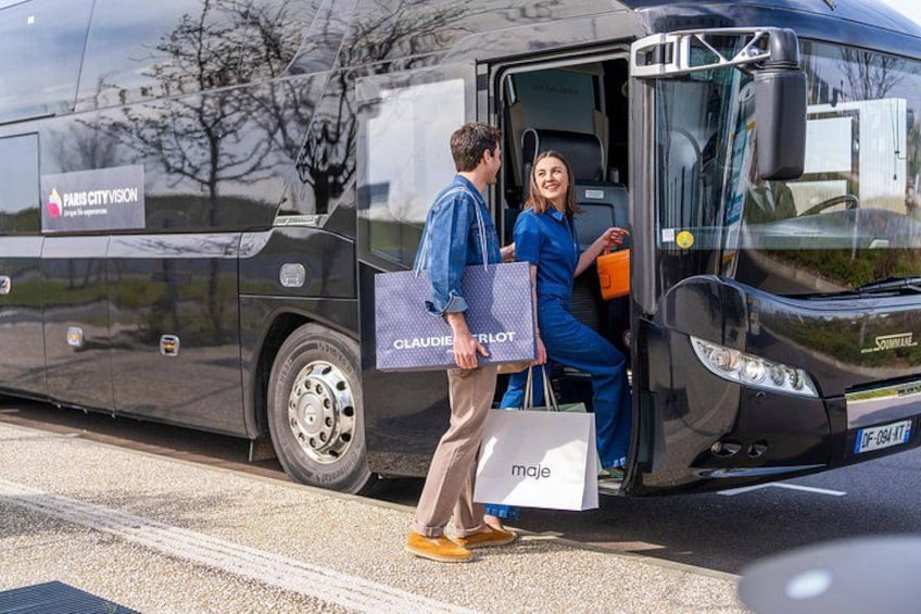 A black bus with 'Paris City Vision' and 'Claude Delvot' logos, a man in a blue jacket and beige pants, and a woman in a blue uniform stepping out. 1