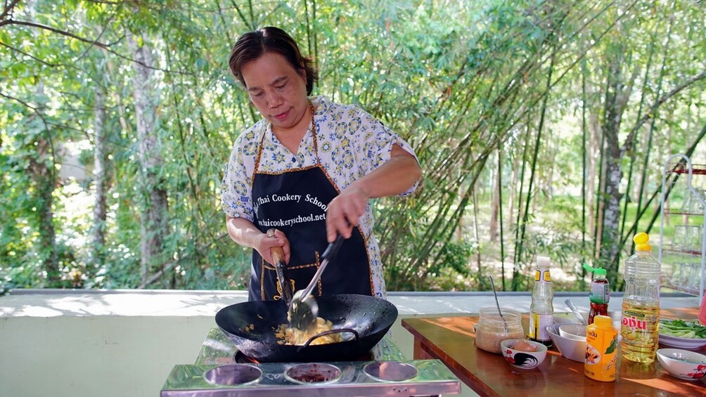 Woman stirs ingredients in wok