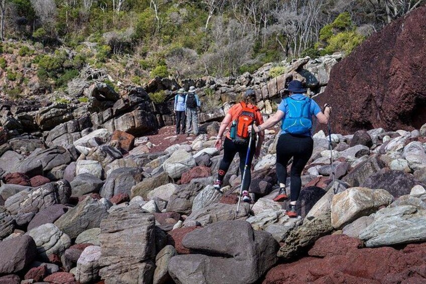 Hikers navigating a rocky terrain with large boulders and sparse vegetation. 3