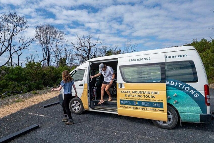A van with a side advertisement for tours, parked on a road with trees and a clear sky in the background. 4