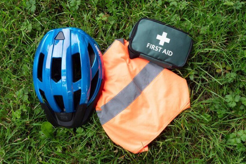 A blue helmet, an orange safety vest, and a first aid kit on grass. 4