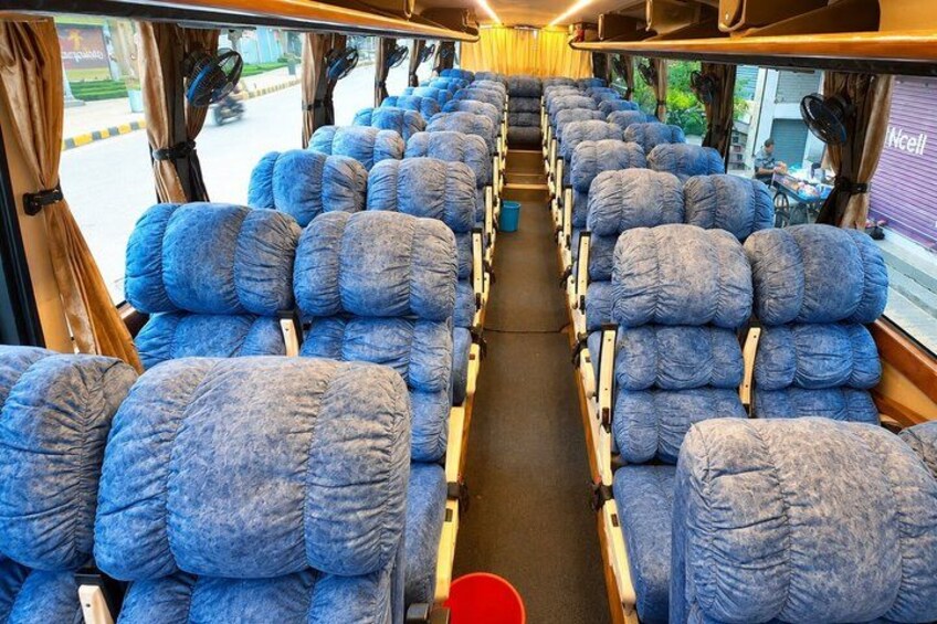 A train interior with rows of blue upholstered seats and a central aisle. 3