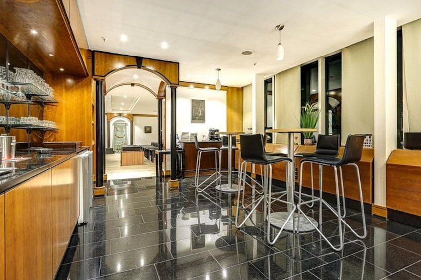 A modern bar area with black-tiled flooring, wooden accents, and bar stools. 2