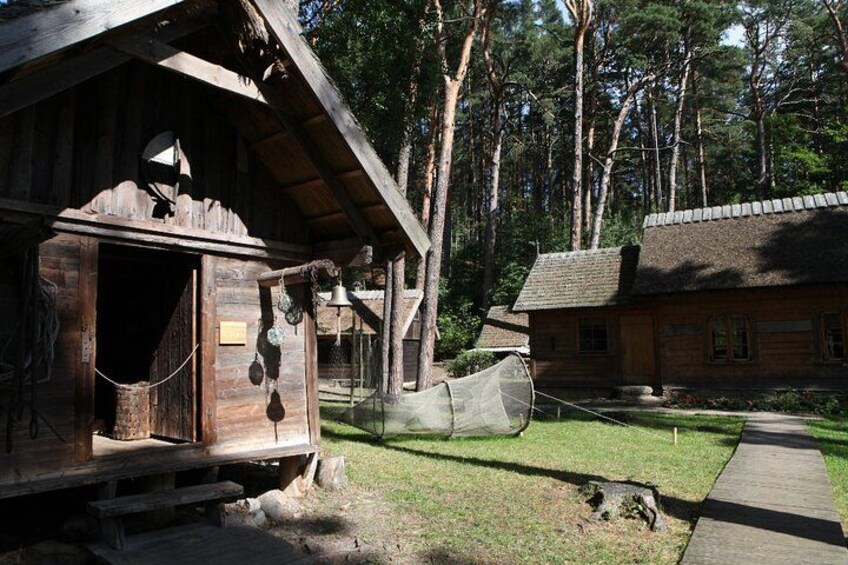 A rustic wooden cabin with a thatched roof, surrounded by a forest. 4