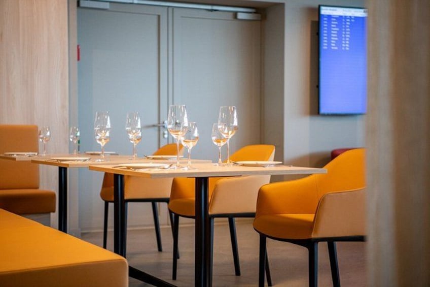 A modern dining area with tables set for six, each with six wine glasses. 5