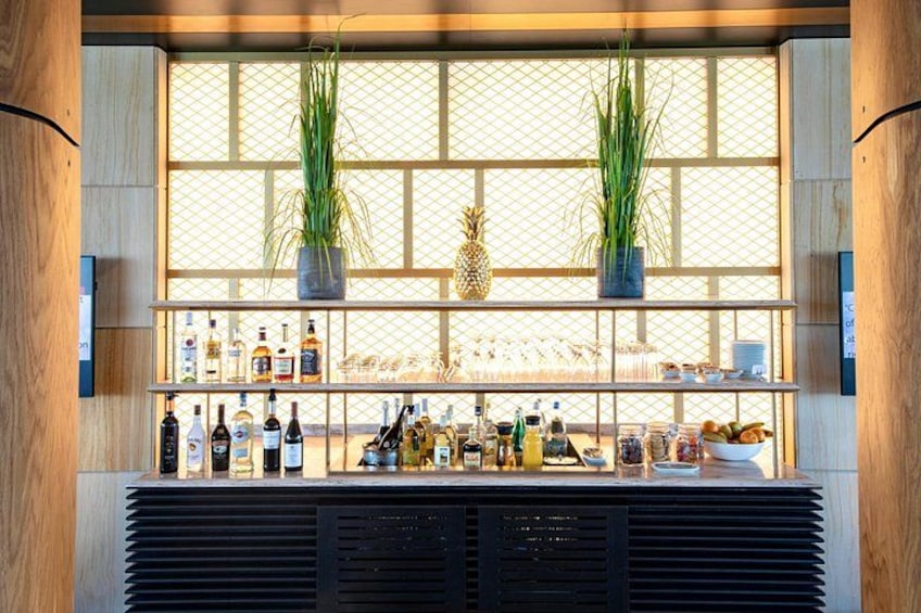 A bar with shelves of bottles, a pineapple decoration, and two potted plants. 4