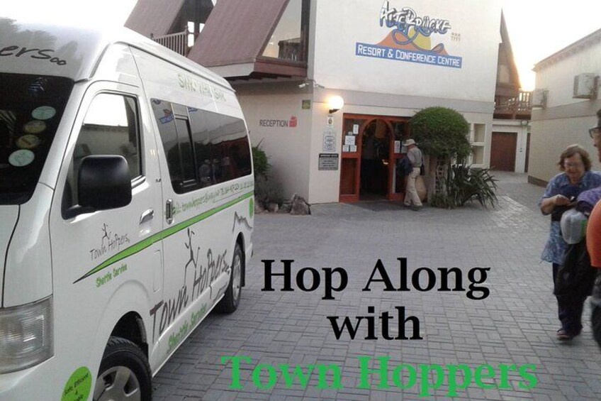 A white van with 'TOW HOPPERS' branding parked in front of a building with a sign that reads 'Resort & Conference Centre.' 1