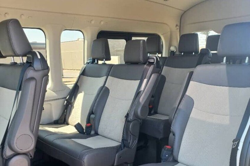 A vehicle interior with multiple seats, headrests, and seat belts. 4