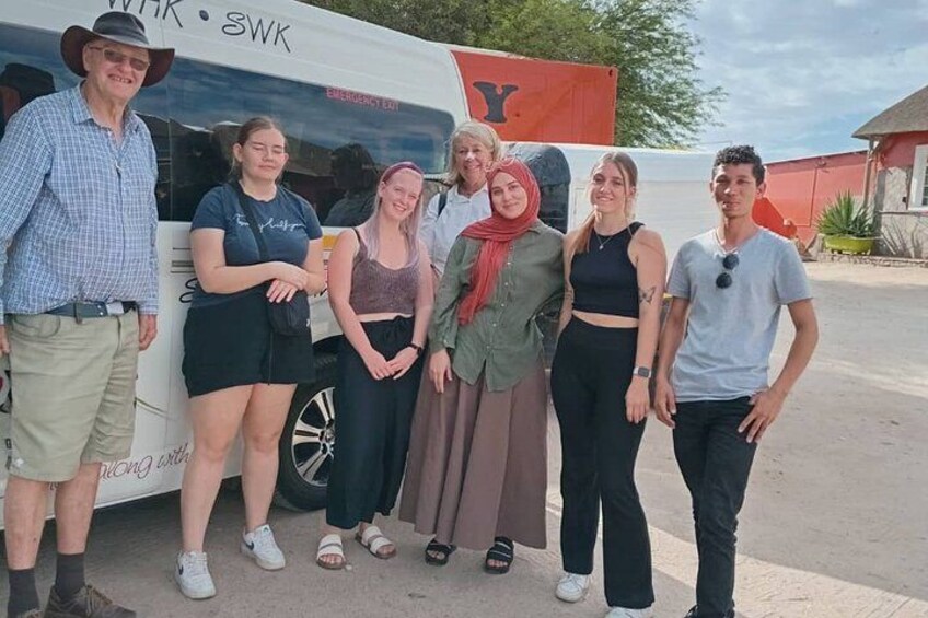 A group of people standing in front of a bus with the letters 'WK' and 'SWK' on it. 2