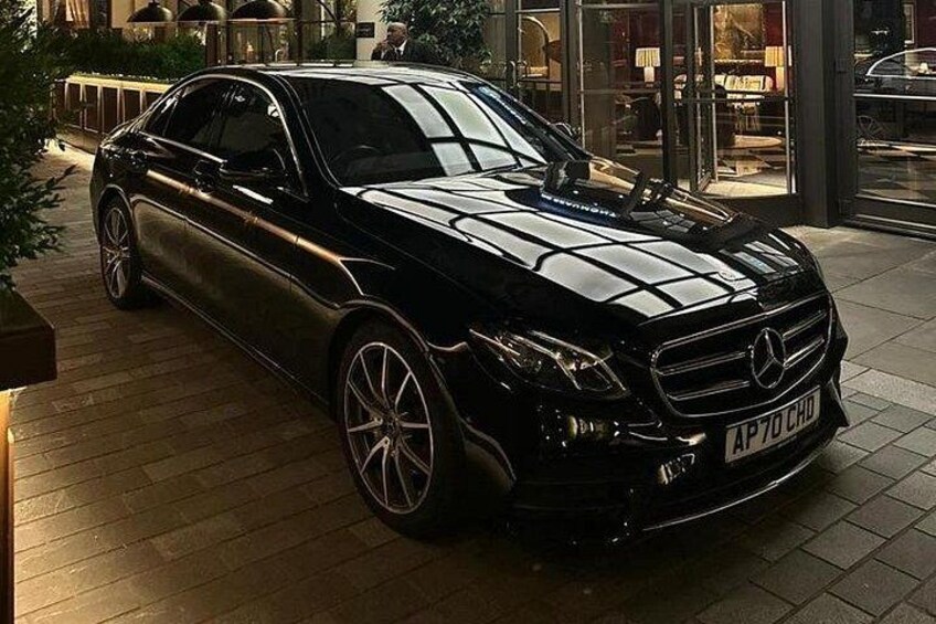 A black Mercedes-Benz parked in front of a building with glass doors. 5