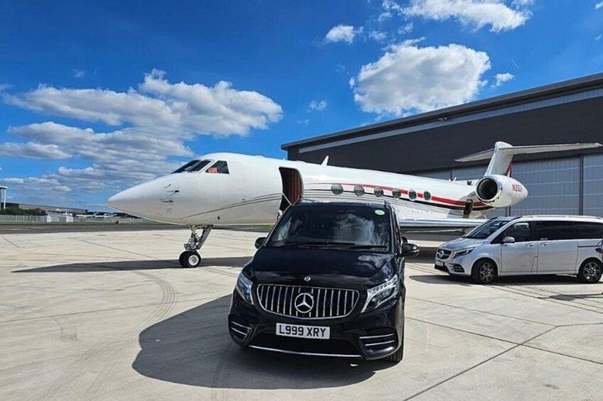 A black Mercedes-Benz SUV parked in front of a private jet on a tarmac. 2