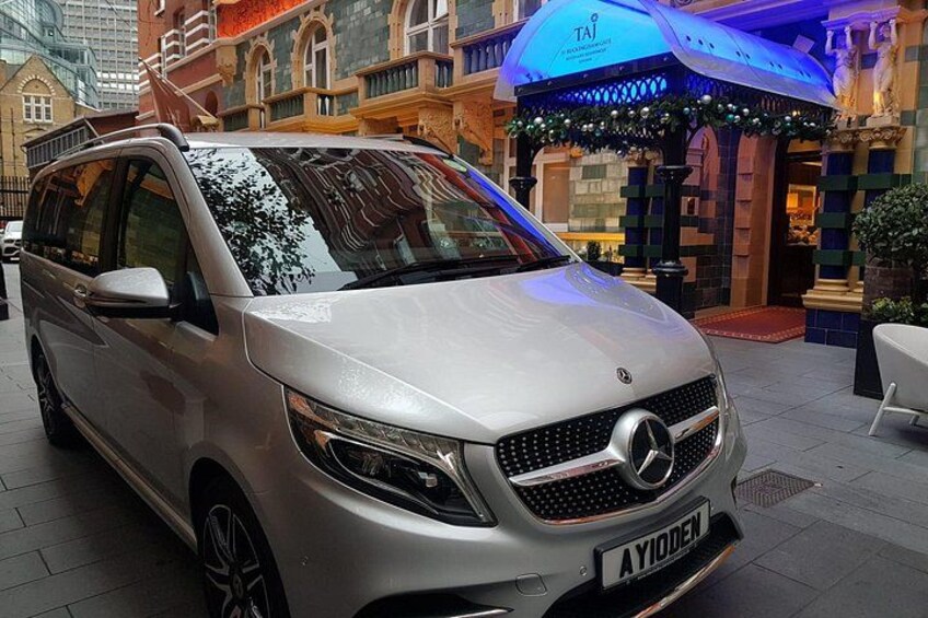 A silver Mercedes-Benz van parked in an urban setting with classical architecture in the background. 3