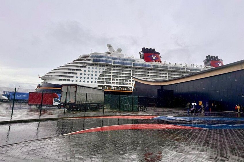 A large cruise ship docked at a port with a covered walkway and a bicycle. 4