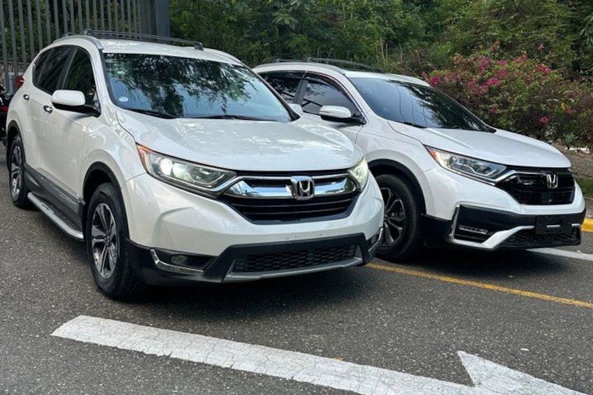 Two white Honda CR-V SUVs parked on a road with a white line marking. 4