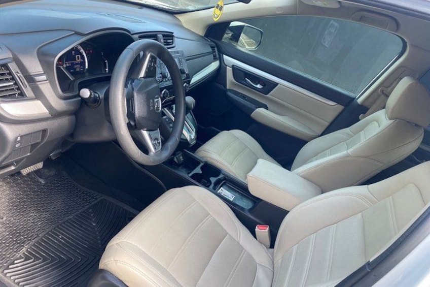 A car's interior with beige leather seats, a steering wheel, dashboard, and center console. 3