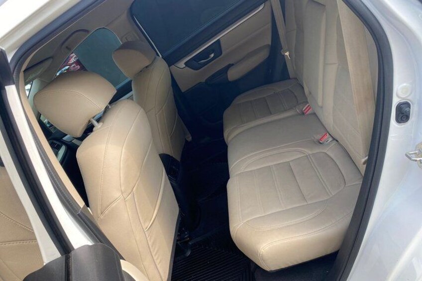 A car's interior with beige leather seats and a visible seatbelt. 2