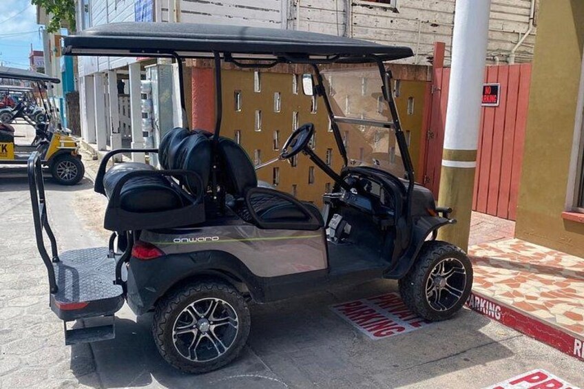A golf cart parked on a street with a 'No Parking' sign and a 'Reserved Parking' sign. 1