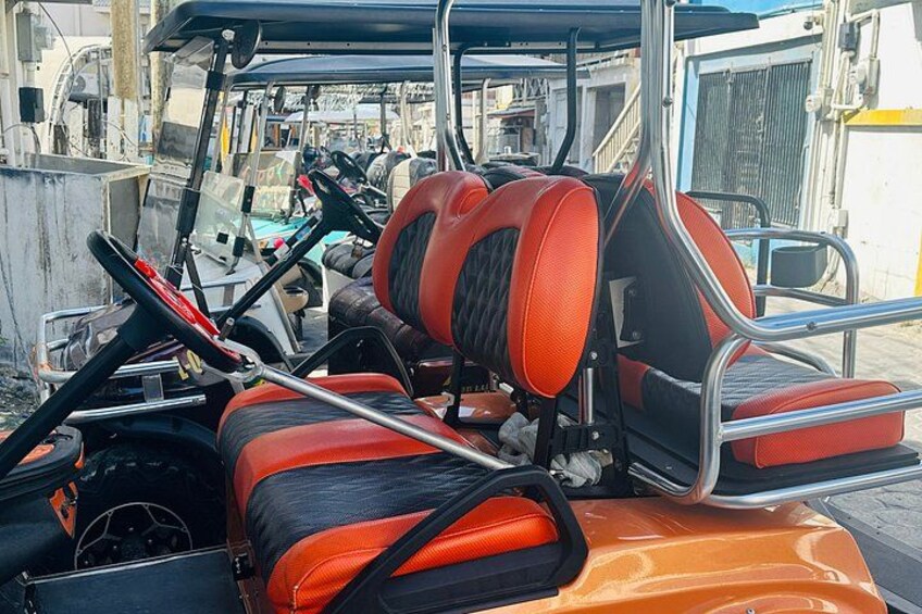 A golf cart with red and black seats, a steering wheel, and a metal frame. 4