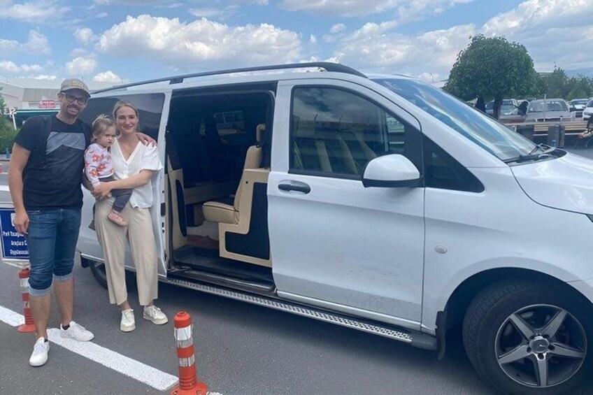 A white van with its door open, a person standing next to it, and a child in the background. 2