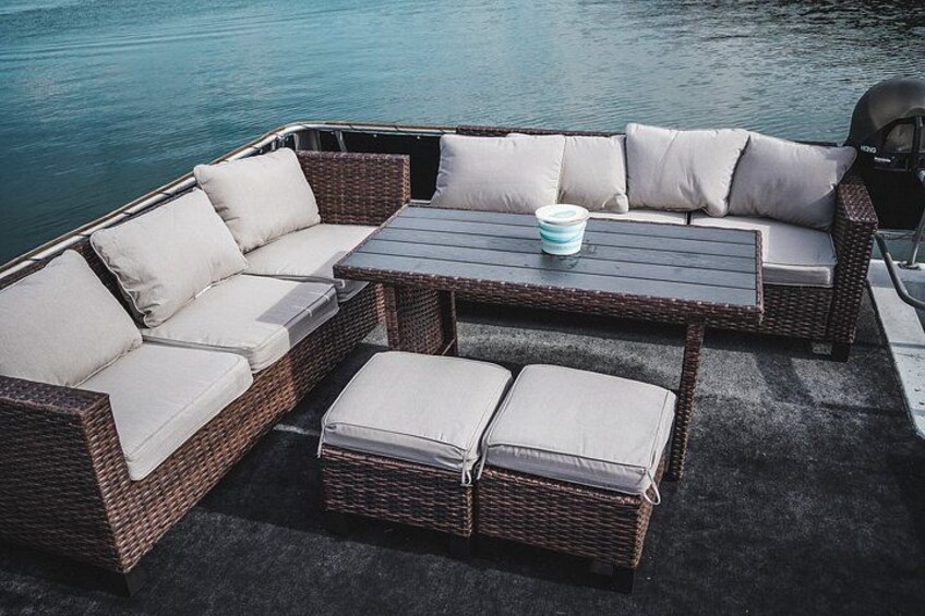 A wicker boat with a cushioned seating area and a table. 1