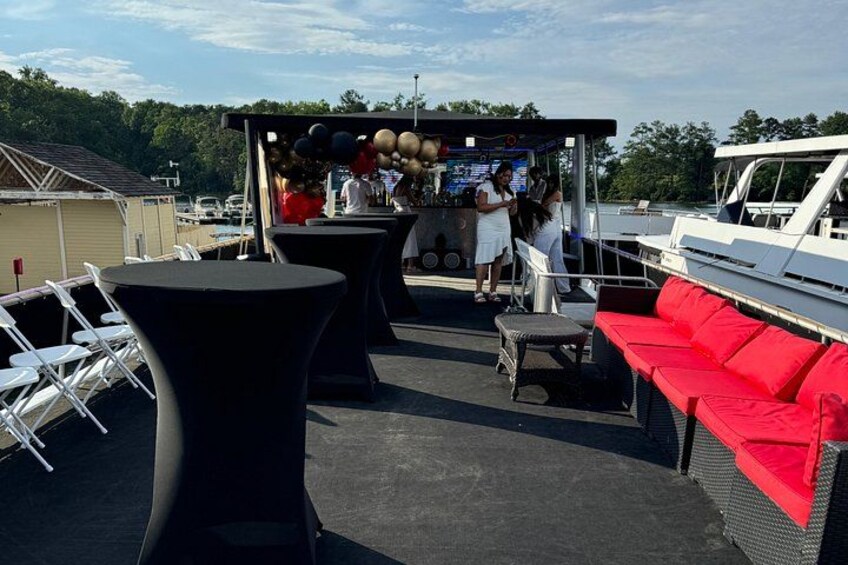 An outdoor bar area with round tables, red cushioned seating, and a bar counter with balloons. 5