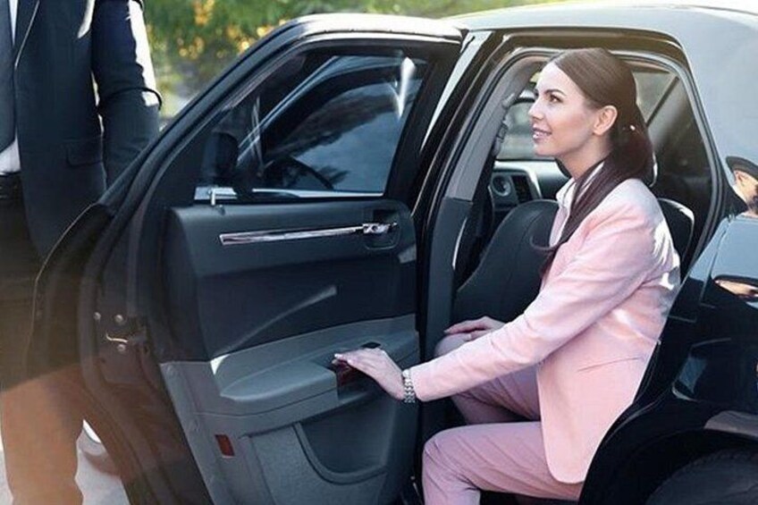 A person in a pink suit sitting in a car with a door open. 4