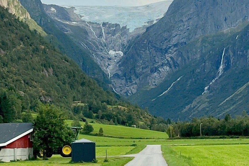 A rural landscape with a road, a barn, a tractor, and a waterfall. 1