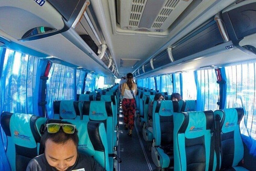 A bus interior with blue seats and a person walking down the aisle. 2