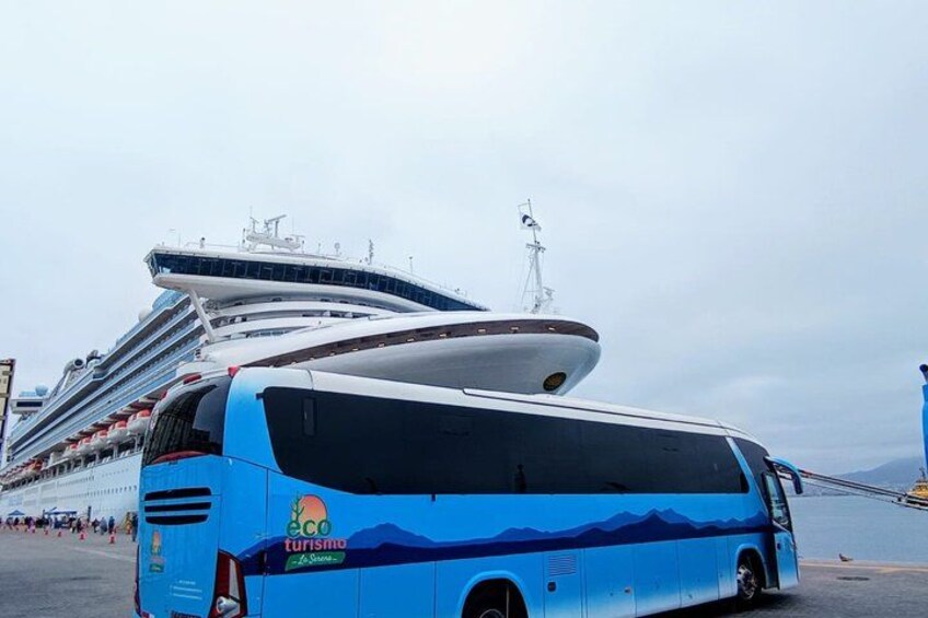 A blue bus with 'eco tourism' written on it parked next to a cruise ship. 1