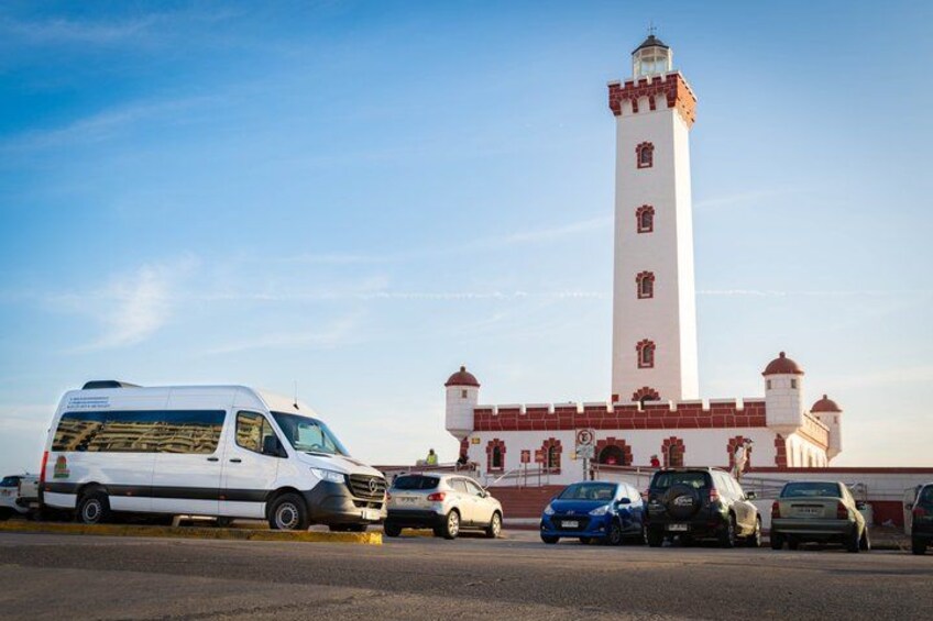 A white van, several cars, and a tall white tower with red accents. 2