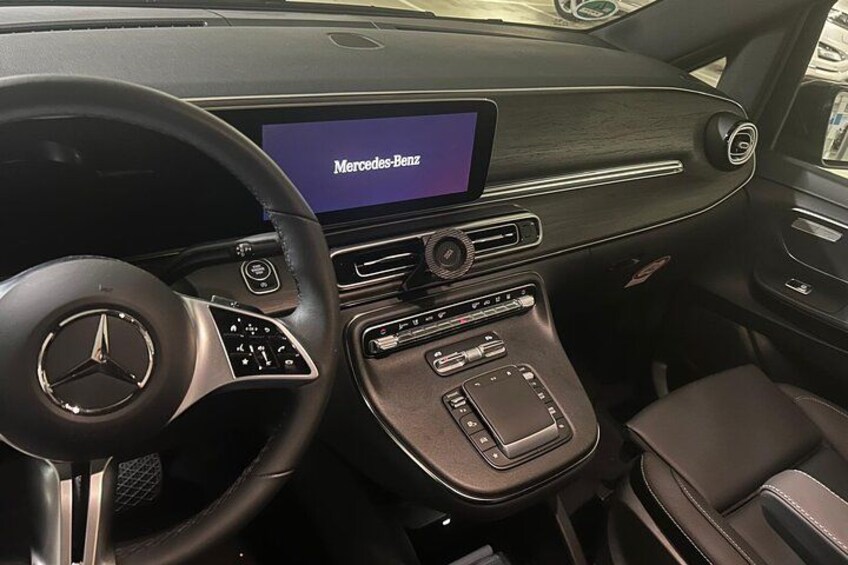 A Mercedes-Benz car interior with a digital display, leather seats, and a central console. 2