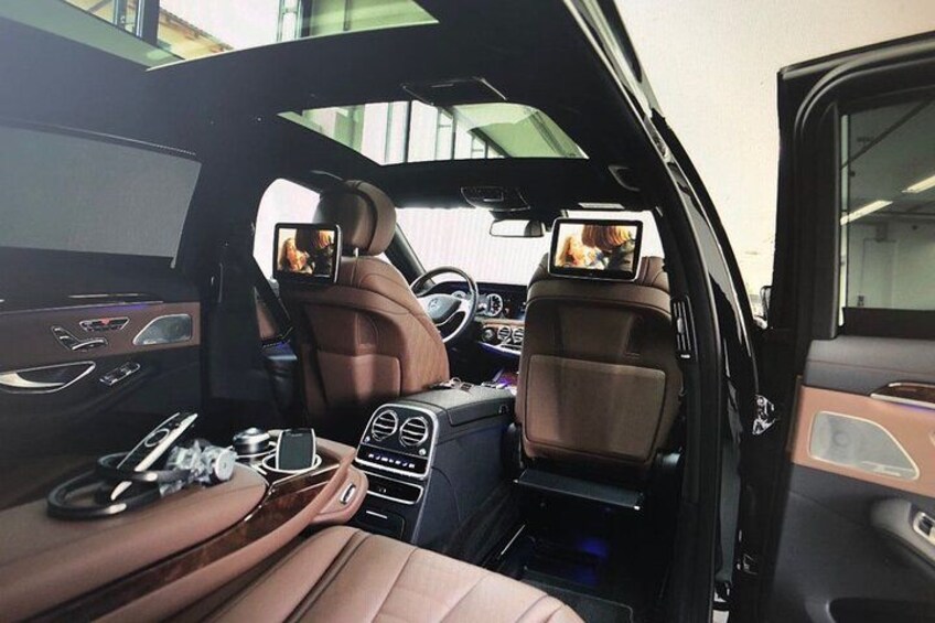 A car interior with leather seats, a steering wheel, a dashboard, and a rearview mirror. 3
