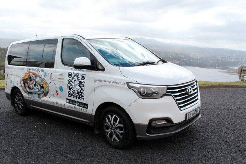 A white van parked on a road with a QR code and a website URL on the side. 1
