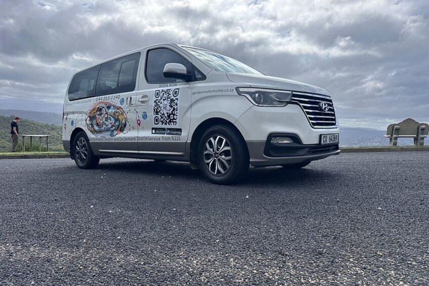 A white van parked on a road with a QR code and a colorful design on its side. 3