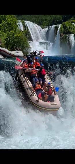 A group of people in a raft navigating through a waterfall. 1