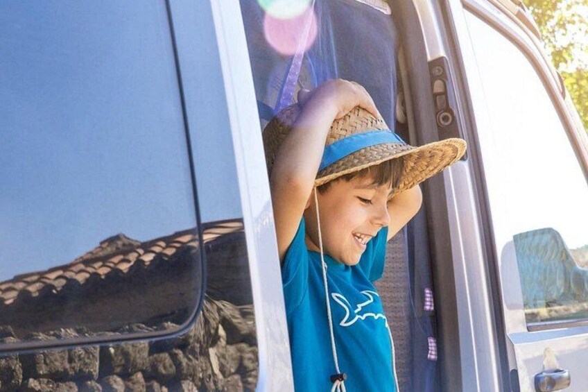 A person in a blue shirt and straw hat sitting in a vehicle. 1