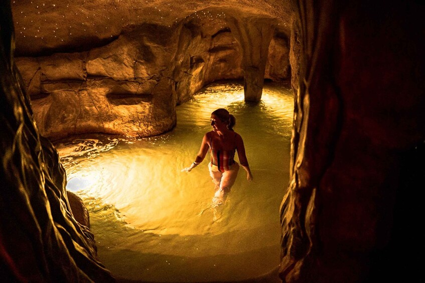 A person in a cave with water and illuminated by warm lighting. 3