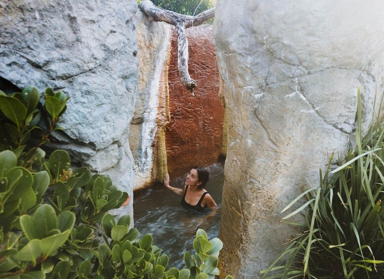 A person in a natural water pool surrounded by rocks and greenery. 5
