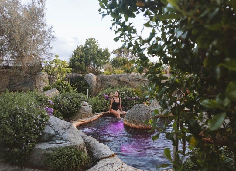 A person sitting by a water feature surrounded by rocks and greenery. 5