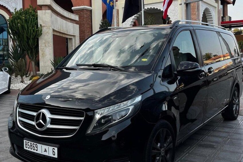 A black Mercedes-Benz SUV parked in front of a building with a flag. 3