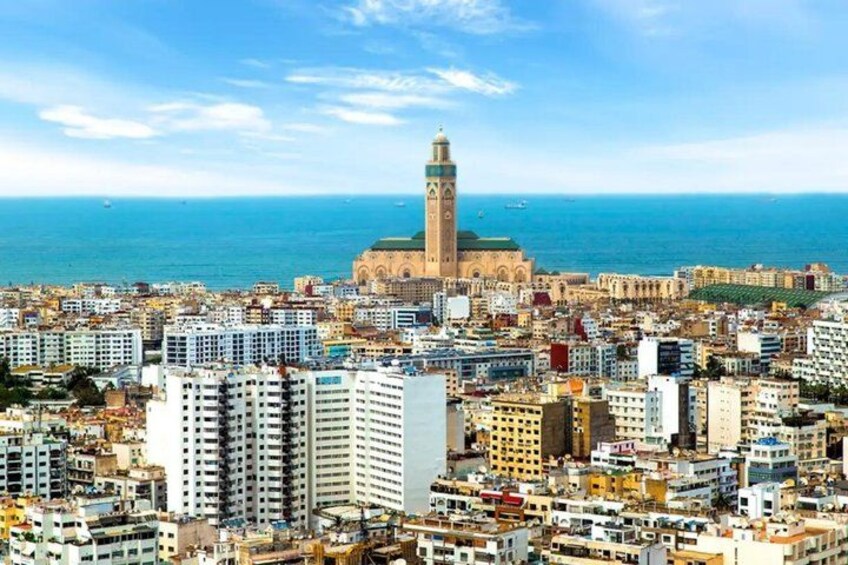 A coastal cityscape with a prominent tower and a mosque with a minaret. 2