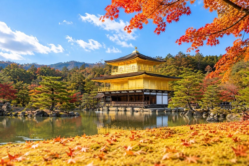 Et traditionelt japansk tempel med en gylden facade, omgivet af en rolig sø og efterårsfarver. 2