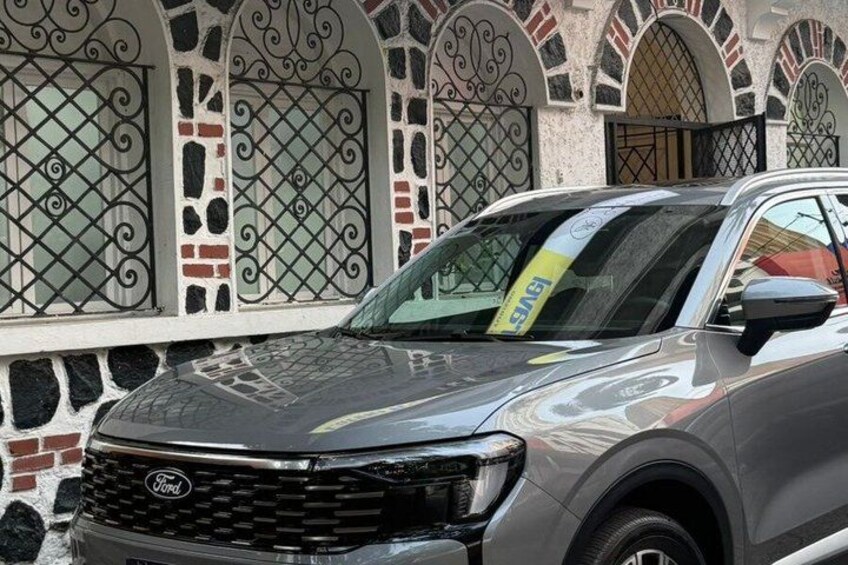A gray Ford SUV parked in front of a building with decorative ironwork windows. 4