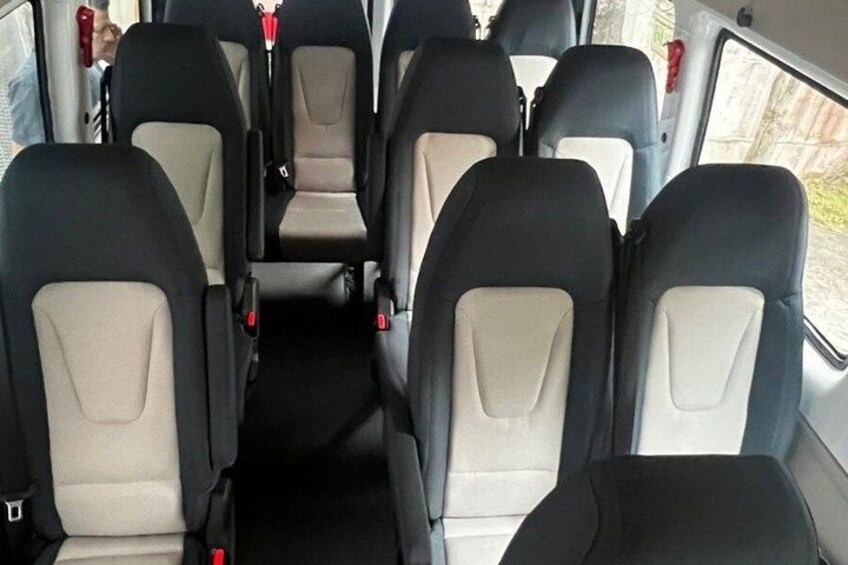 A bus interior with six rows of seats, each with a headrest and seatbelt. 3