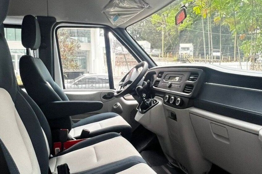 A vehicle interior with a steering wheel, dashboard, and seats. 5