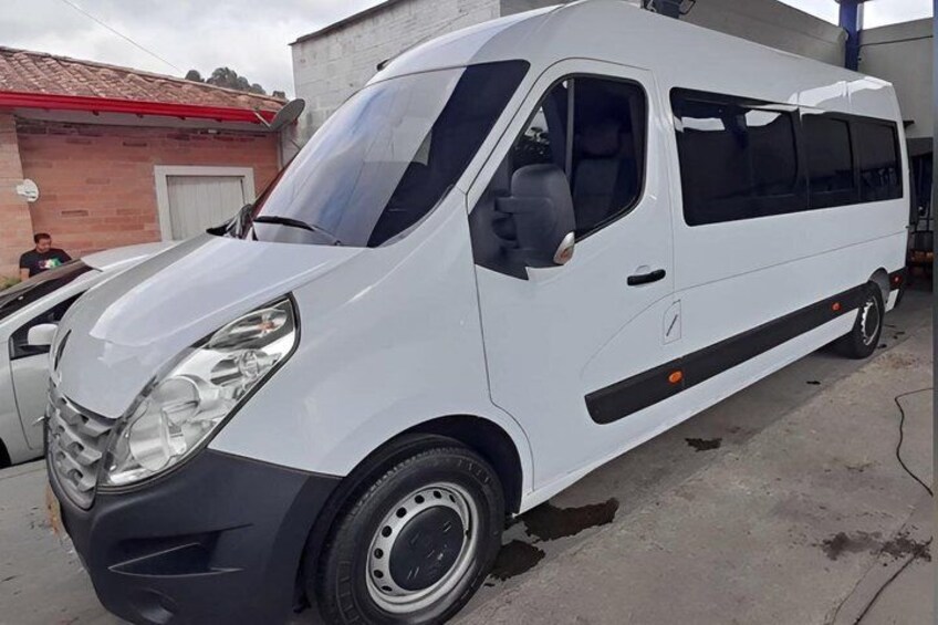 A white van parked in an industrial area with a brick building in the background. 2