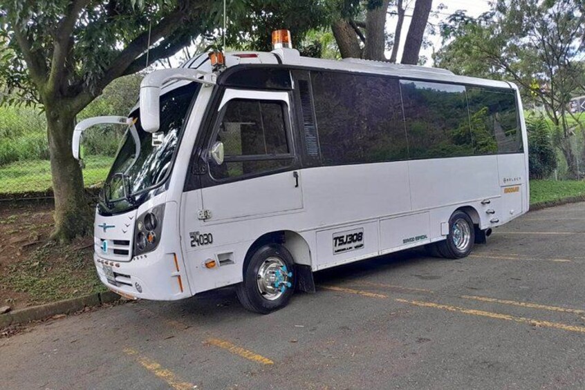 A white bus parked on a road with trees in the background. 3